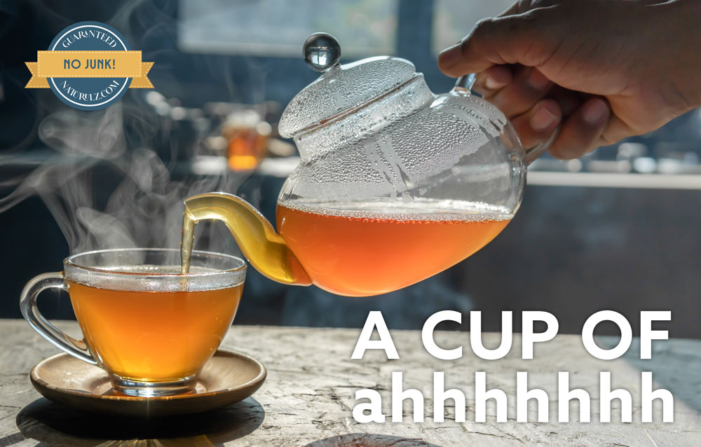 A person pouring tea into a cup on top of a table.