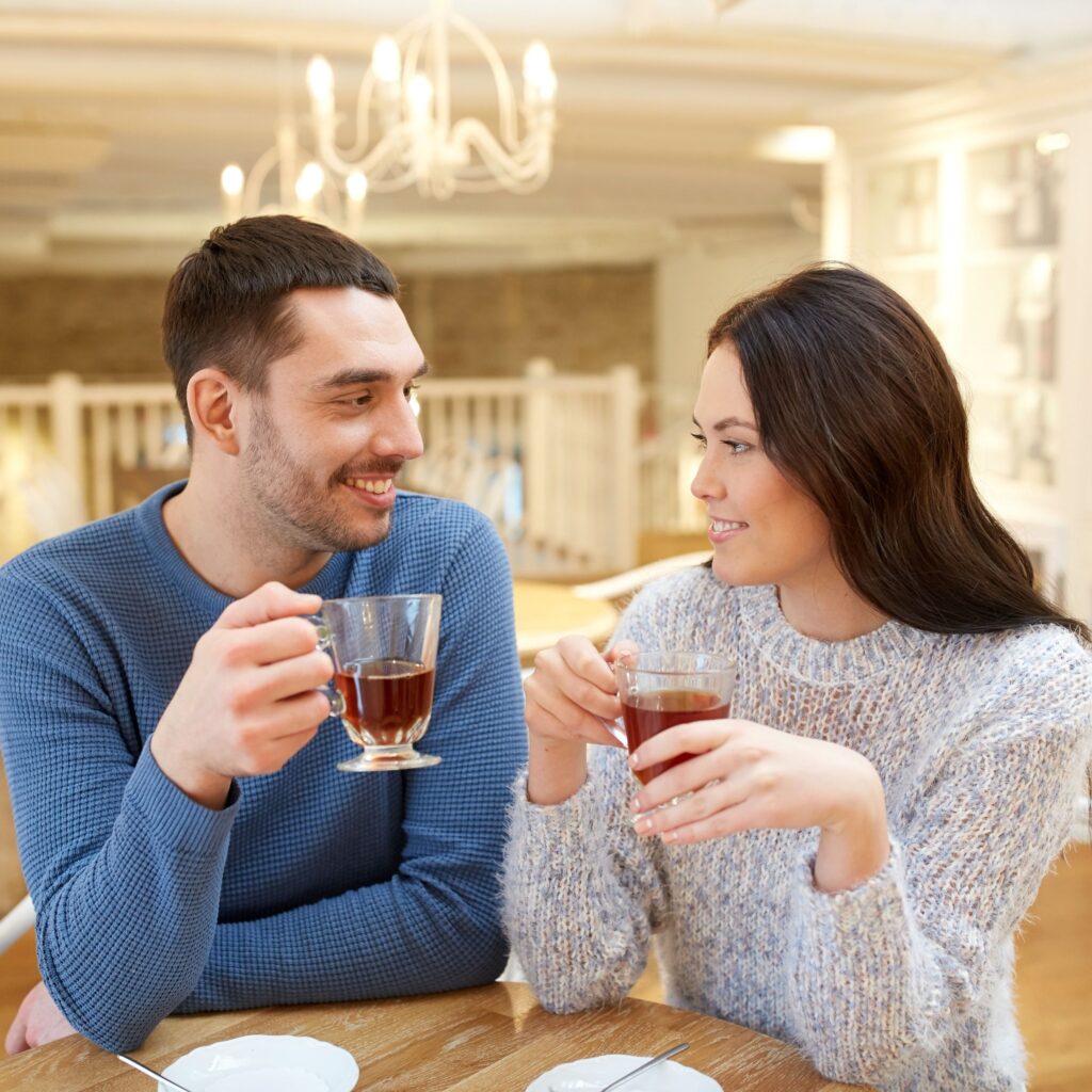 A man and woman sitting at a table drinking wine.